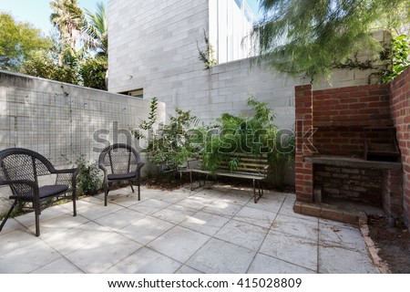 Small Australian apartment courtyard with paving and cane outdoor chairs
