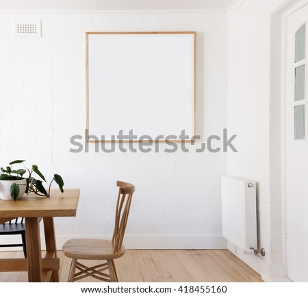 Blank framed print on white wall in beautiful danish styled interior dining room