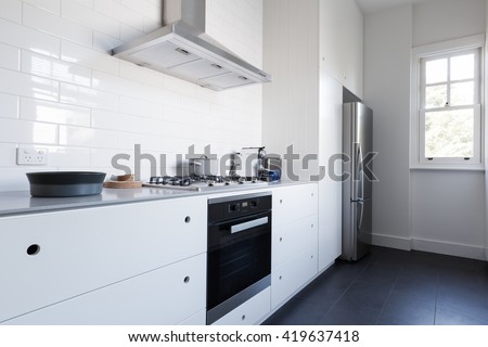 Monochrome clean white kitchen bench top and cupboards with appliances