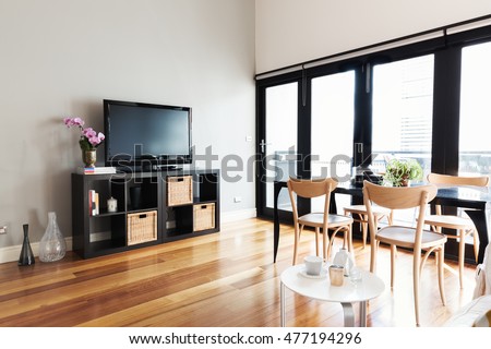 Modern apartment living room with tv on buffet and bi fold door to balcony
