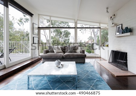 Mid century modern living room with huge windows to view the Australian treetops