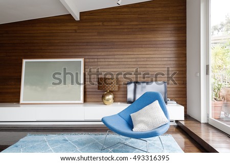 Horizontal wood panelling and blue occasional chair in mid century modern living room