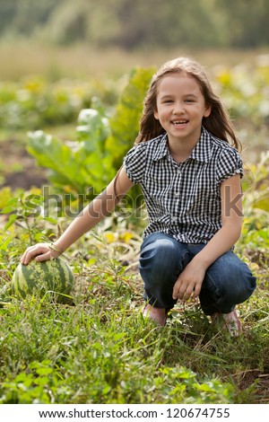 A child sits next to the watermelon in the garden