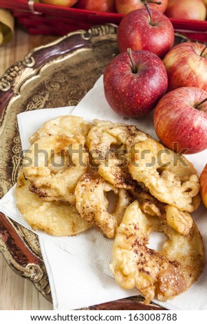 Apple fritters on an elegant wooden tray with many fresh apples near