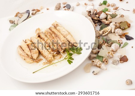 Fish fillets roasted mackerel on a white plate with parsley and shells.