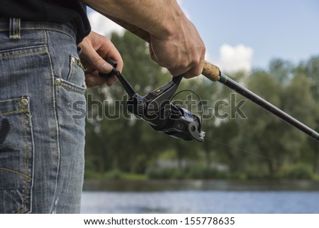 Fisherman holding fishing rod and reel, ready to catch some fish out of the river