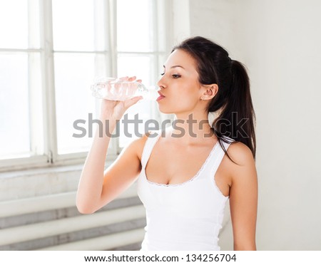 Fitness woman drink water in bottle. Healthy lifestyle photo of  fitness model on white background.