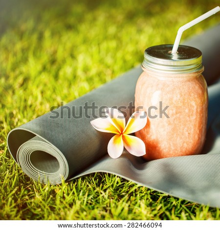 Smoothies and yoga mat on the grass