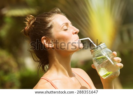 Woman drinking water detox dressed in sports clothes