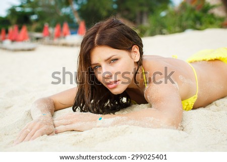 Relaxing beach woman enjoying the summer sun in swimsuit. Glamorous girl with gold tattoo on the hand.