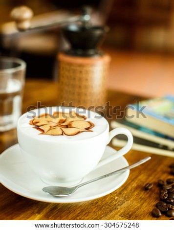 Cappuccino with fresh coffee beans, water and books on a brown background