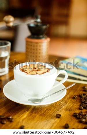 Cappuccino with fresh coffee beans, water and books on a brown background