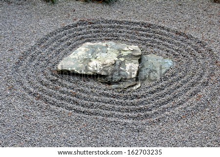 Zen garden of pebbles and sand around rock
