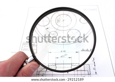Reviewing technical drawing with magnifying glass. Focus on magnifying glass.