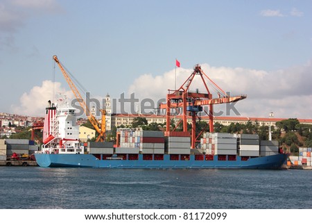Large container ship in a dock at port - Side view (all copyrighted logos and brand names removed)