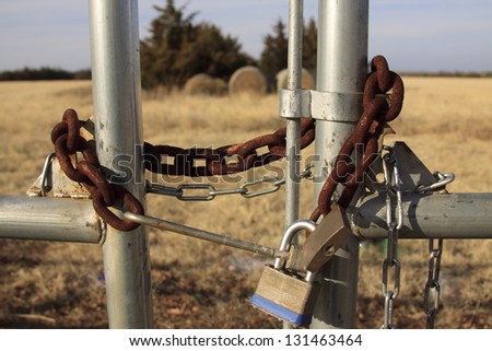 Rusted chain and lock secure an old farm gate.