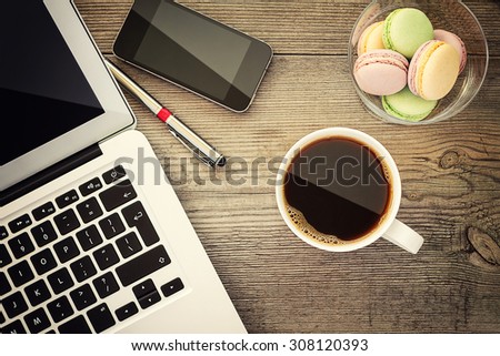 Laptop, cup of coffee and cookies on the wooden background