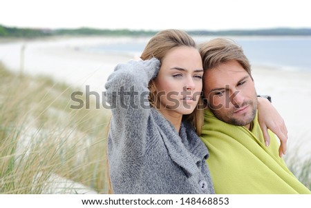 The attractive lovely woman and man sit in the sand dune of a beach relaxing - autumn, beach, sea