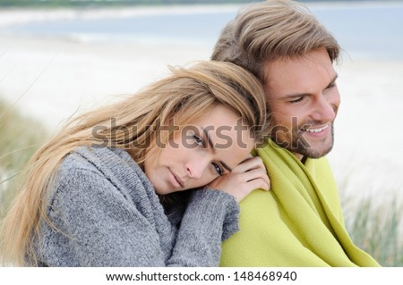 The attractive lovely woman and man sit in the sand dune of a beach relaxing - autumn, beach, sea