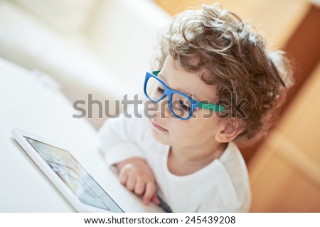 Cute boy in white t-shirt, wearing glasses, watching fairy tale - light background. Lovely little scientist