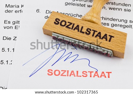 a stamp made of wood lying on a document. german words: welfare