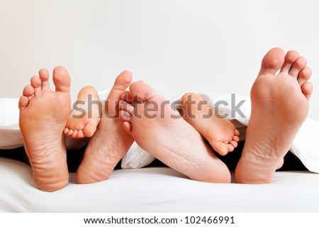 the soles of a family in bed under the covers.