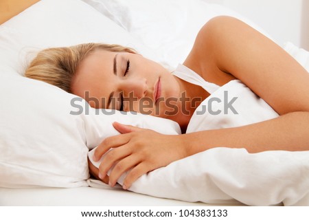 a pretty young woman sleeping in bed recovering.