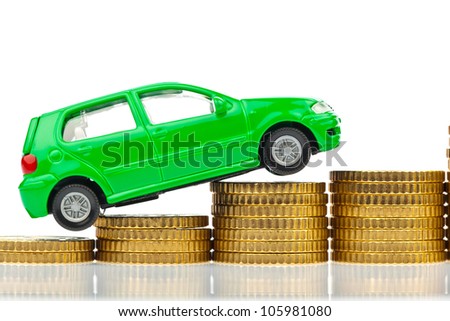 a model car is on coins. rising costs for gasoline car prices, insurance and taxes.