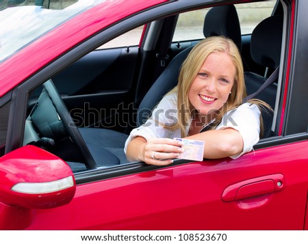 a young woman proudly displays her license. license and new car.