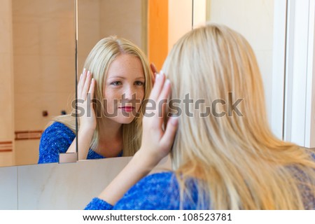 a young woman is familiar with a brush her long blonde hair in the bathroom