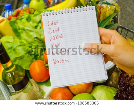 a woman holding a shopping list in a supermarket in the hand. german language.