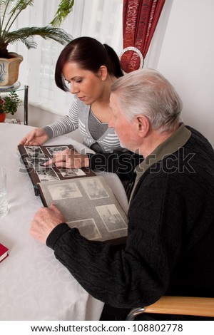 a young woman looks at a photo album with seniors