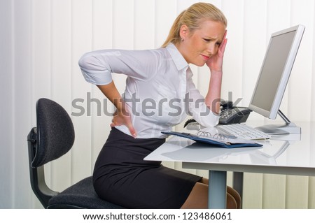 a woman with back pain from sitting so long in the office. health and welfare at work.