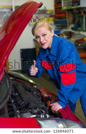 a young woman as a mechanic in a garage. rare professions for women. car is being repaired in the workshop