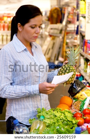 Woman with shopping list in a supermarket and shopping trolleys