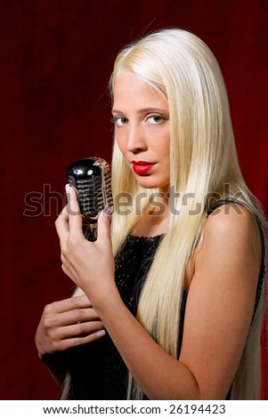 Young woman with a microphone as a singer in evening gown