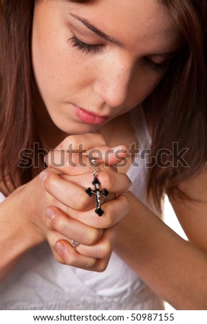 Young girls clasped hands in prayer with a cross, a young girl clasped hands in prayer with a cross