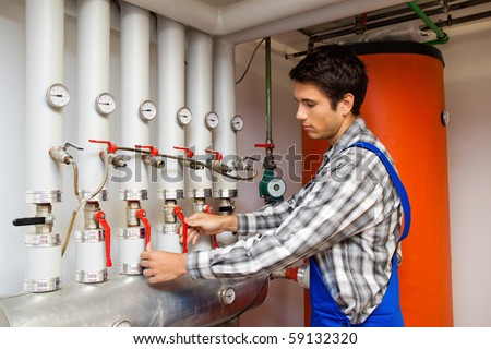 Designroom on Young Heating Engineer In A Boiler Room For Heating System Stock Photo