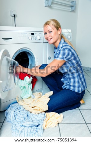 A young housewife with washing machine and clothes. Washing day.