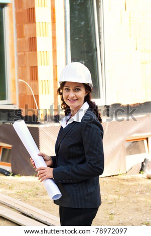 Architect with blueprint before shell of a house in house construction.