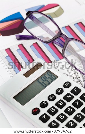 a calculator with graphics of a balance sheet. sales, profit and operating costs.