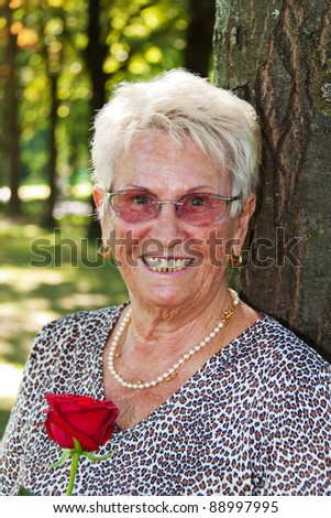happy elderly senior citizen holding a red rose.