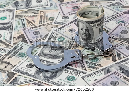 dollar currency notes and handcuffs as a symbol of economic crime