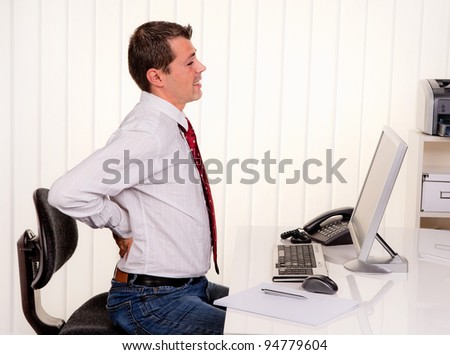 young man in office with computer and back pain