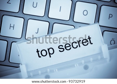 the one hanging folder tab before a computer keyboard on top secret