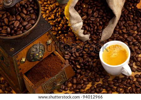 many coffee beans are next to a coffee grinder. freshly ground coffee