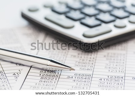 a calculator is on a balance sheet numbers are statistics. photo icon for sales, profit and cost.