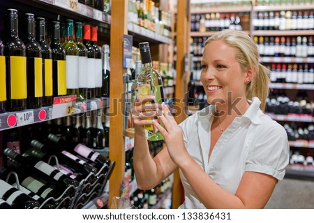 a woman buys wine in a supermarket. wine shelf with wines from around the world.
