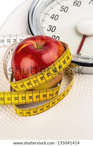 on a bathroom scale is an apple. symbolic photo for weight loss and healthy, vitamin-rich diet.