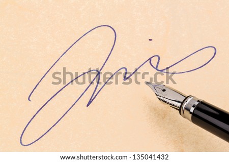 a fountain pen and a signature on yellow paper. symbolic photo for contract testament and graphology